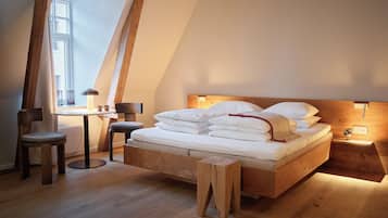 A bedroom with a wooden bed, a small table, a chair, and a window with natural light.
