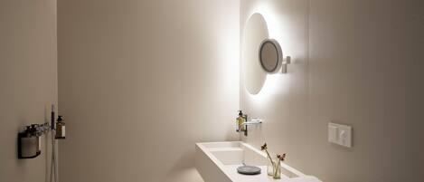 Un baño moderno con ducha, lavamanos y espejo.