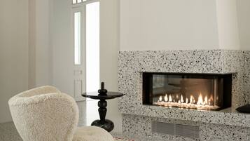 A modern living room with a fireplace, a plush armchair, and a patterned rug.