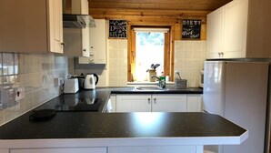 A modern kitchen with white cabinets, a black countertop, and a stainless steel refrigerator. - Astoria (Broadstairs)