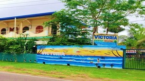 A building with a sign reading "Victoria Guest House" and a mural depicting a beach scene. - Victoria Guest House (Pasikuda)
