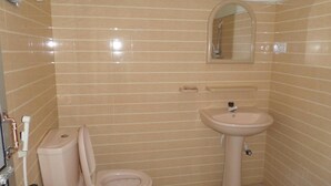 A small bathroom with a toilet, sink, and mirror. - Victoria Guest House (Pasikuda)