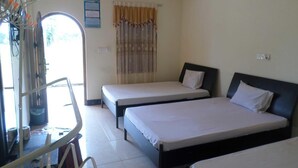 A room with two single beds, a desk with a chair, a window with curtains, and a calendar on the wall. - Victoria Guest House (Pasikuda)