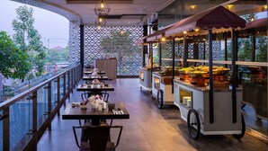 Un restaurante con terraza, un carrito de comida y vistas al verde.