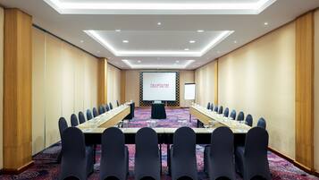 A conference room with a long table, chairs, a projector screen, and a whiteboard.