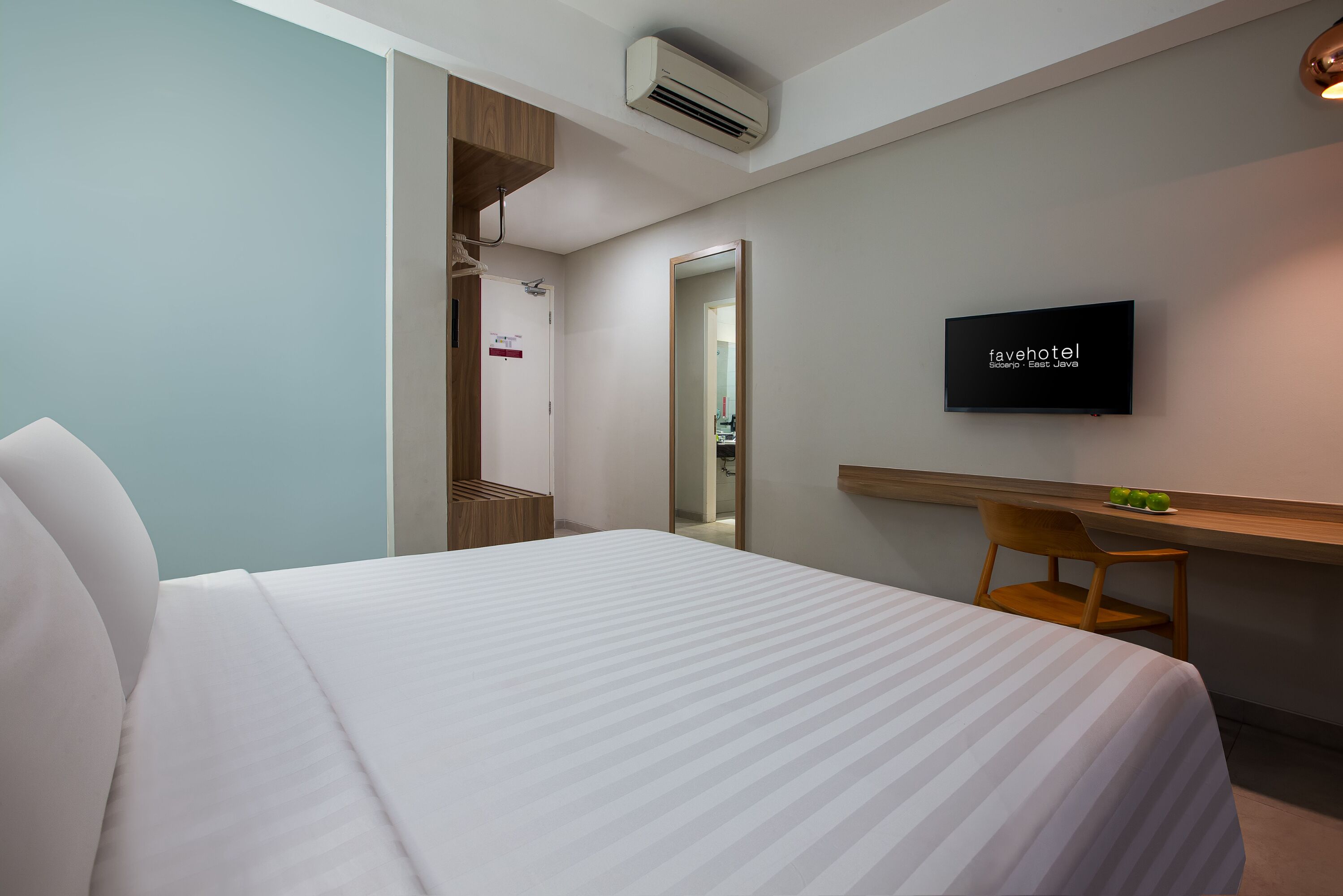 A hotel room with a bed, a TV, a desk, and a chair.