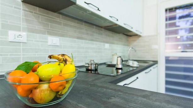 A kitchen with a glass bowl containing fruits on a countertop. - Freccia Rossa Bologna Apartment (Bologna)