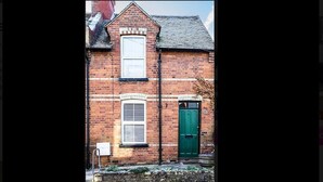 A brick building with a green door and a window with a white frame. - Prospect Place (Canterbury)