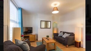 A modern living room with a sofa, coffee table, and TV. - Prospect Place (Canterbury)