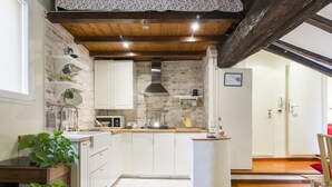 Een keuken met witte kasten, een centraal eiland en een bakstenen muur.