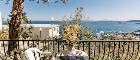 A balcony with a table, chairs, and a view of the sea.