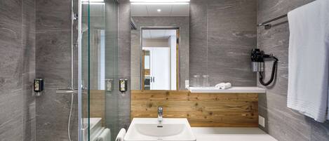 Une salle de bain moderne avec une douche à parois de verre, un meuble-lavabo en bois et un lavabo blanc.