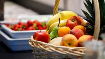 A wicker basket filled with various fruits including apples, bananas, and a pineapple.