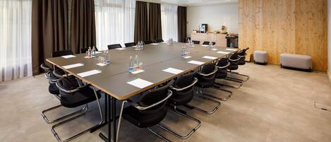 A conference room with a long table, chairs, water bottles, and a projector.