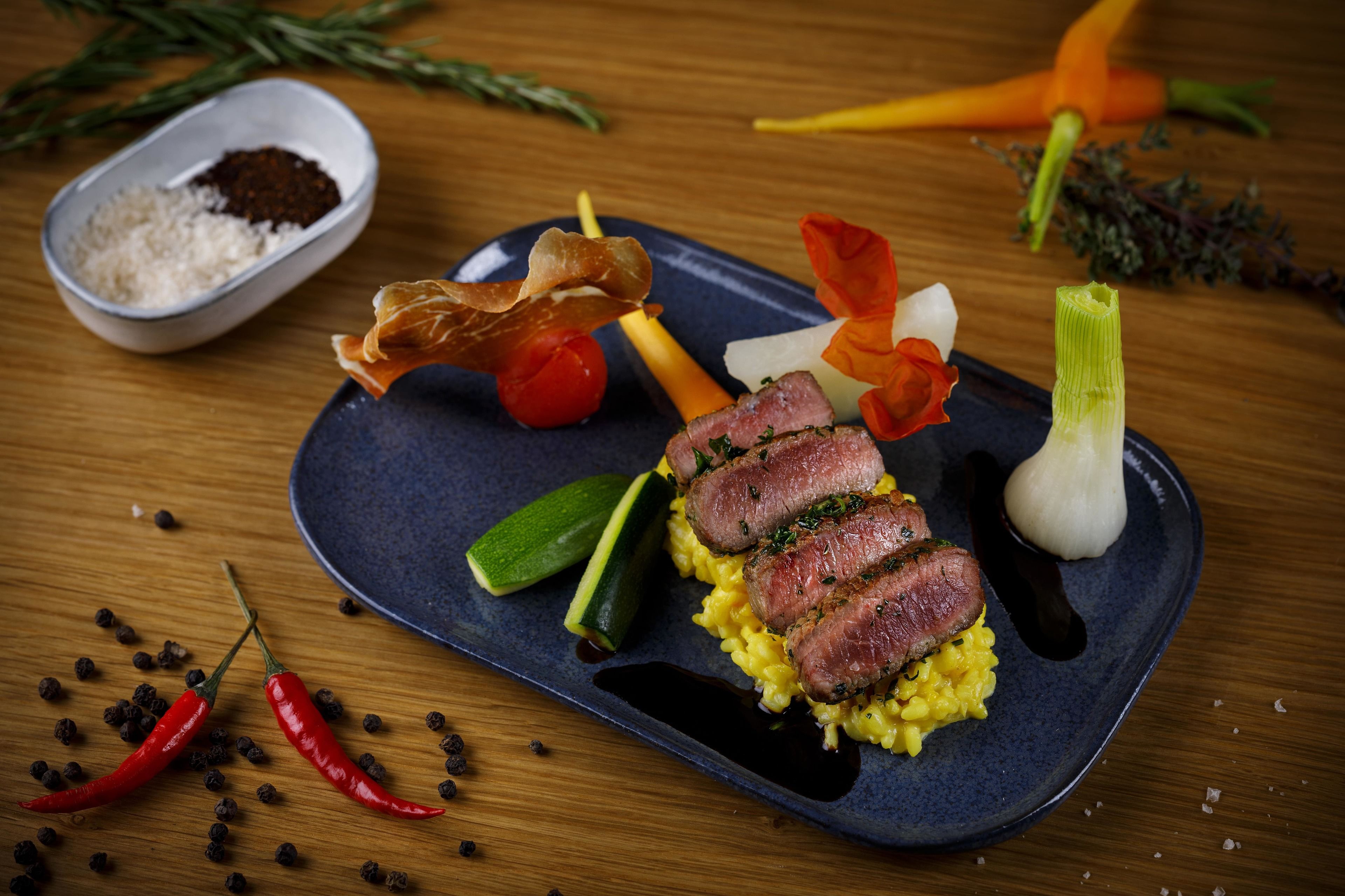 Une assiette de nourriture contenant de la viande, des légumes et des accompagnements, le tout présenté sur une assiette sombre.