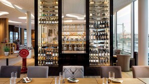 A restaurant with a wine cellar, dining tables, and chairs. - Hotel Allegra Lodge (Kloten)