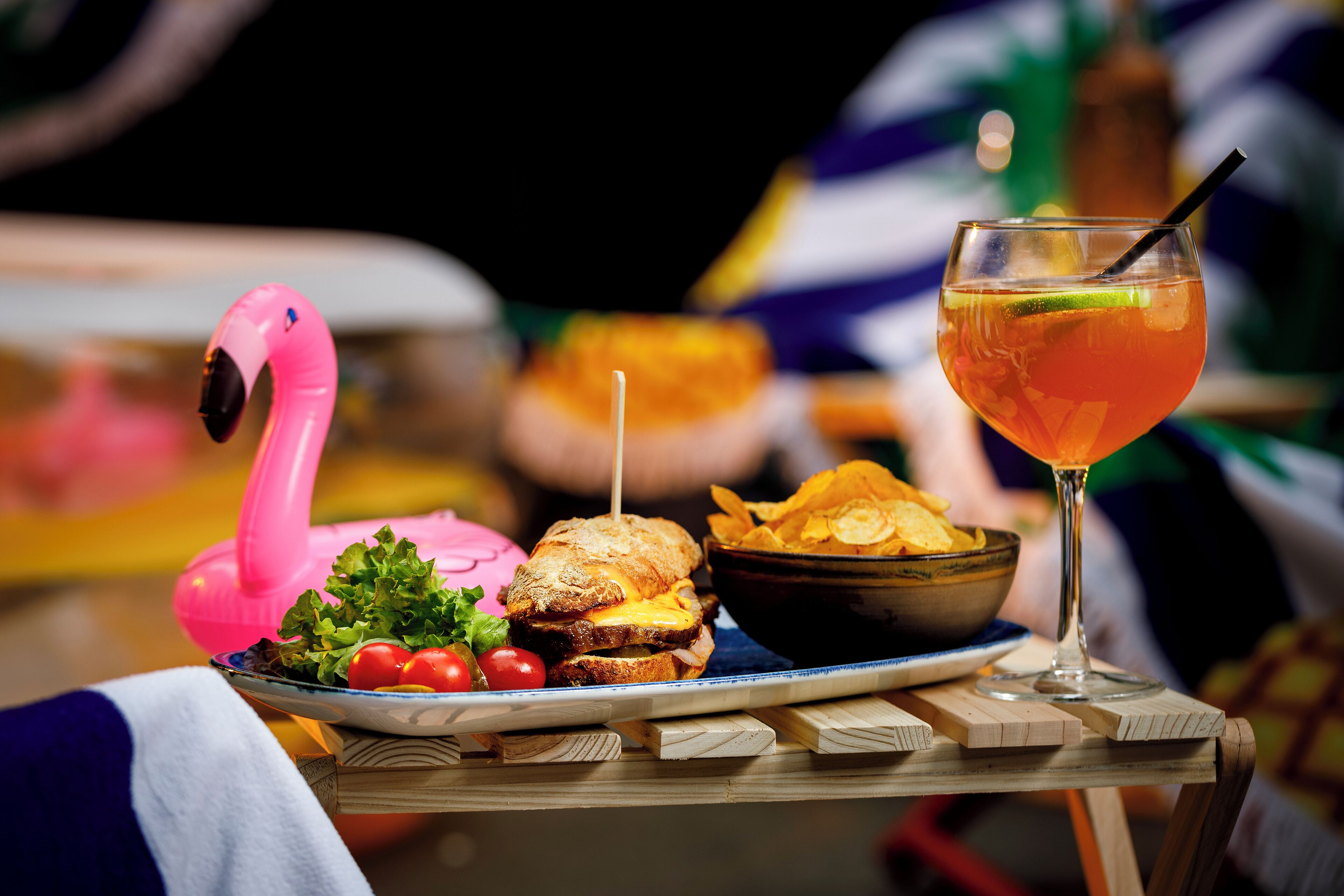 A table with a plate of food, a drink, and a pink flamingo decoration.