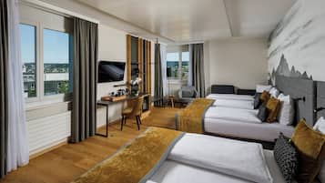 Habitación de hotel con dos camas, un escritorio, una silla, un televisor y ventanas grandes con cortinas.