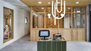 A reception desk with a computer monitor, telephone, and a small plant.