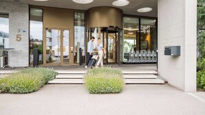 A modern building entrance with a revolving door, glass doors, and a number '5' sign. - Hotel Allegra Lodge (Kloten)