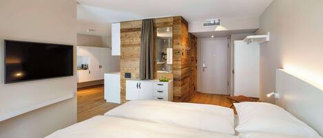 A modern bedroom with a large bed, a TV mounted on the wall, and a wooden accent wall.