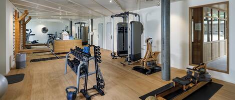 A spacious gym with various exercise equipment, including a rowing machine, kettlebells, and a weight rack.
