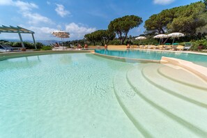 Una piscina al aire libre de temporada, sombrillas, tumbonas