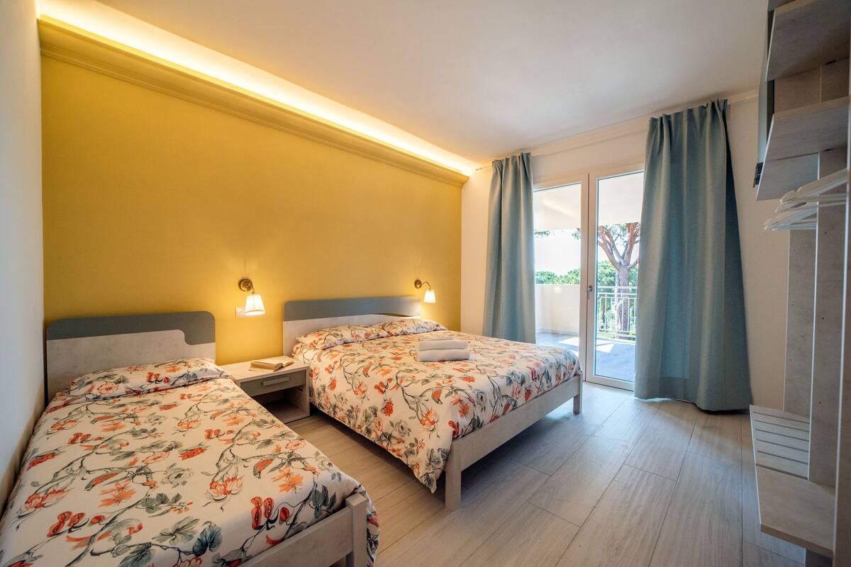 Une chambre d’hôtel avec deux lits, un balcon et une vue sur la verdure.