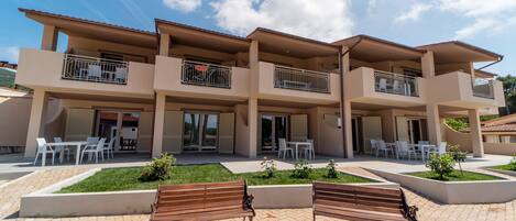 A multi-story building with balconies, outdoor seating, and a paved patio area.
