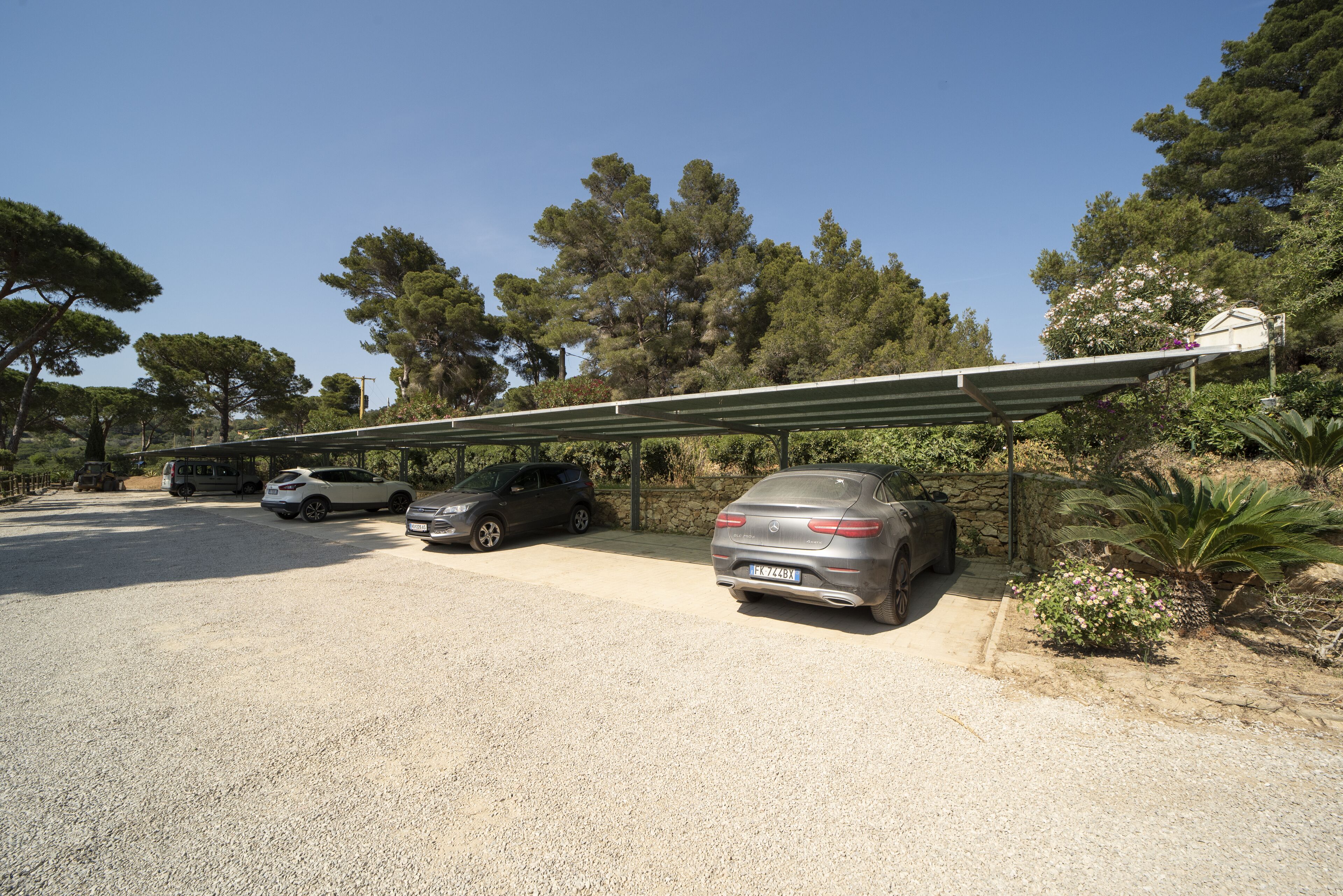 A parking area with several cars, a bus, and a covered walkway.