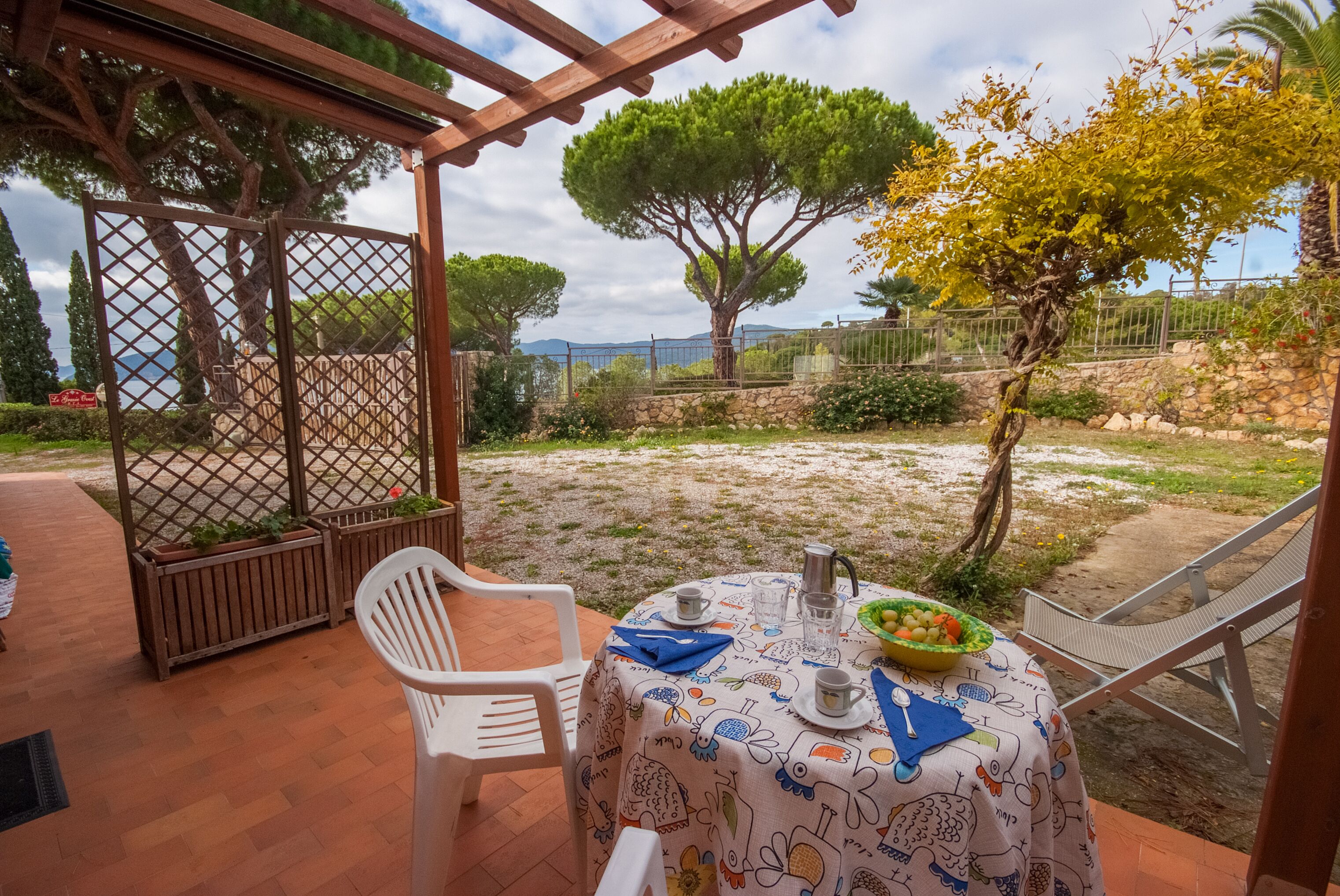 Eine Terrasse mit Esstisch, umgeben von einer Pergola und Blick aufs Meer.
