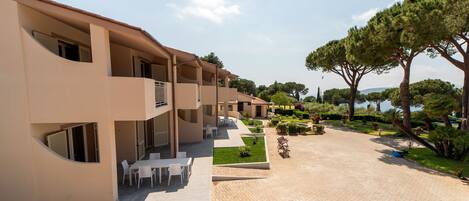 A modern building with multiple balconies, outdoor seating, and a landscaped garden area.