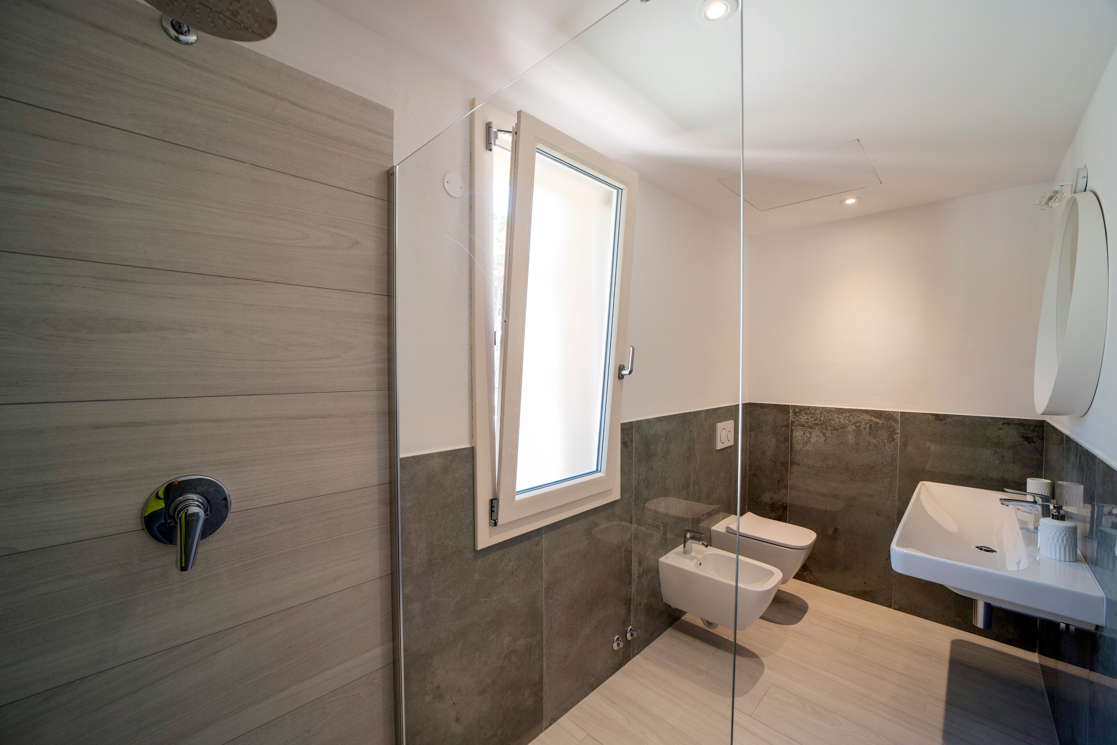 A modern bathroom with a glass shower enclosure, a toilet, and a sink.