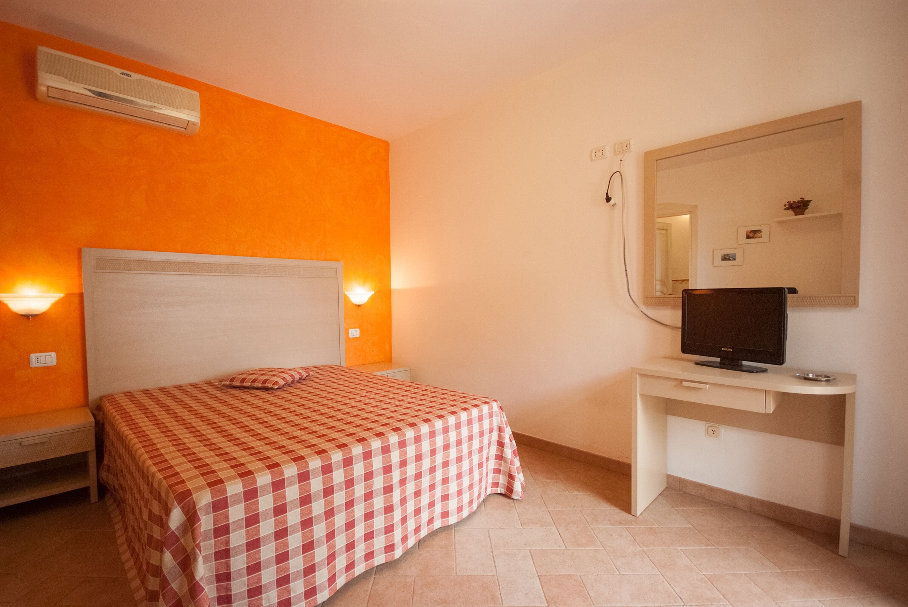 Une chambre à coucher avec un lit, un bureau, un ordinateur et un climatiseur.