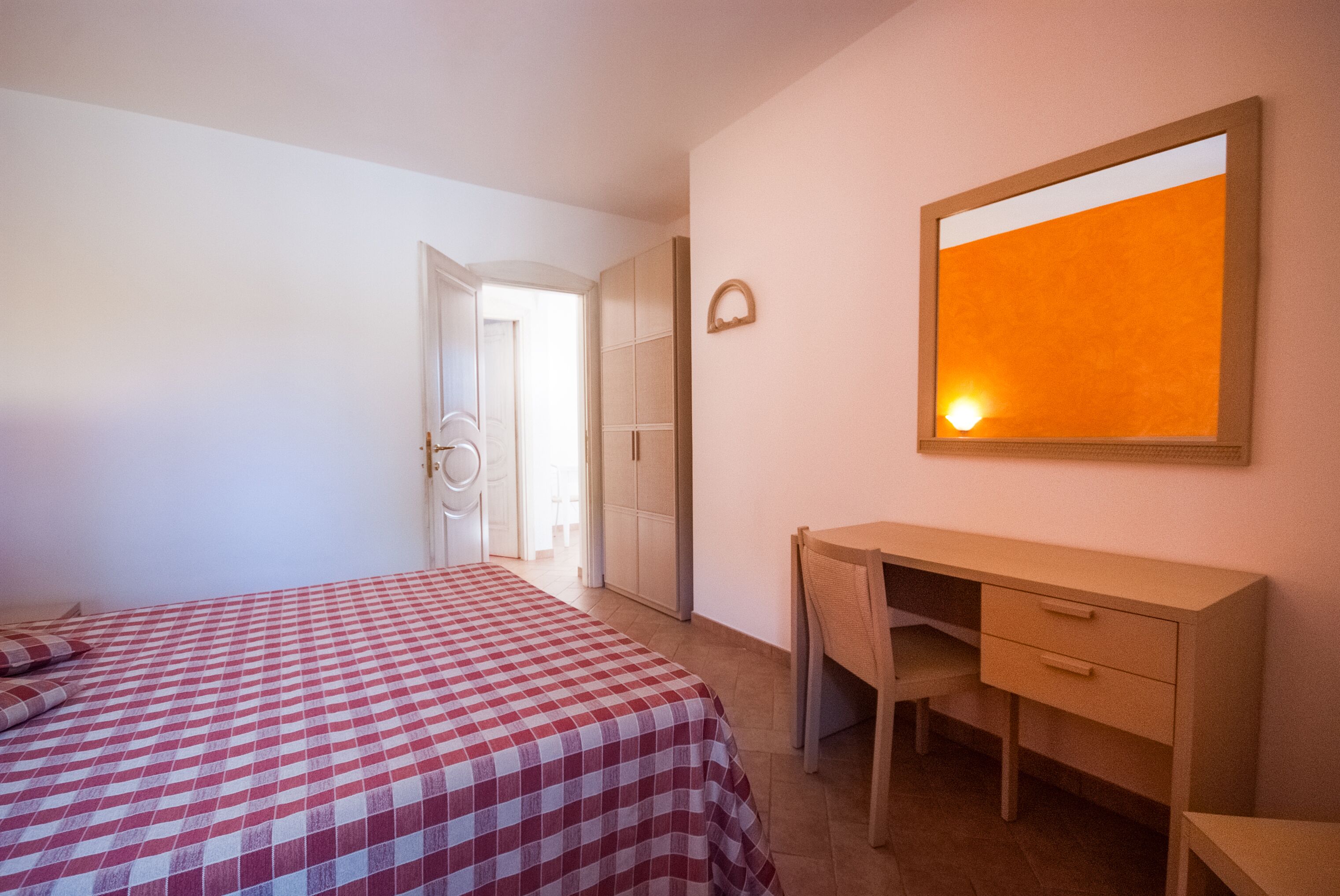 A bedroom with a bed, a desk, and a wardrobe.