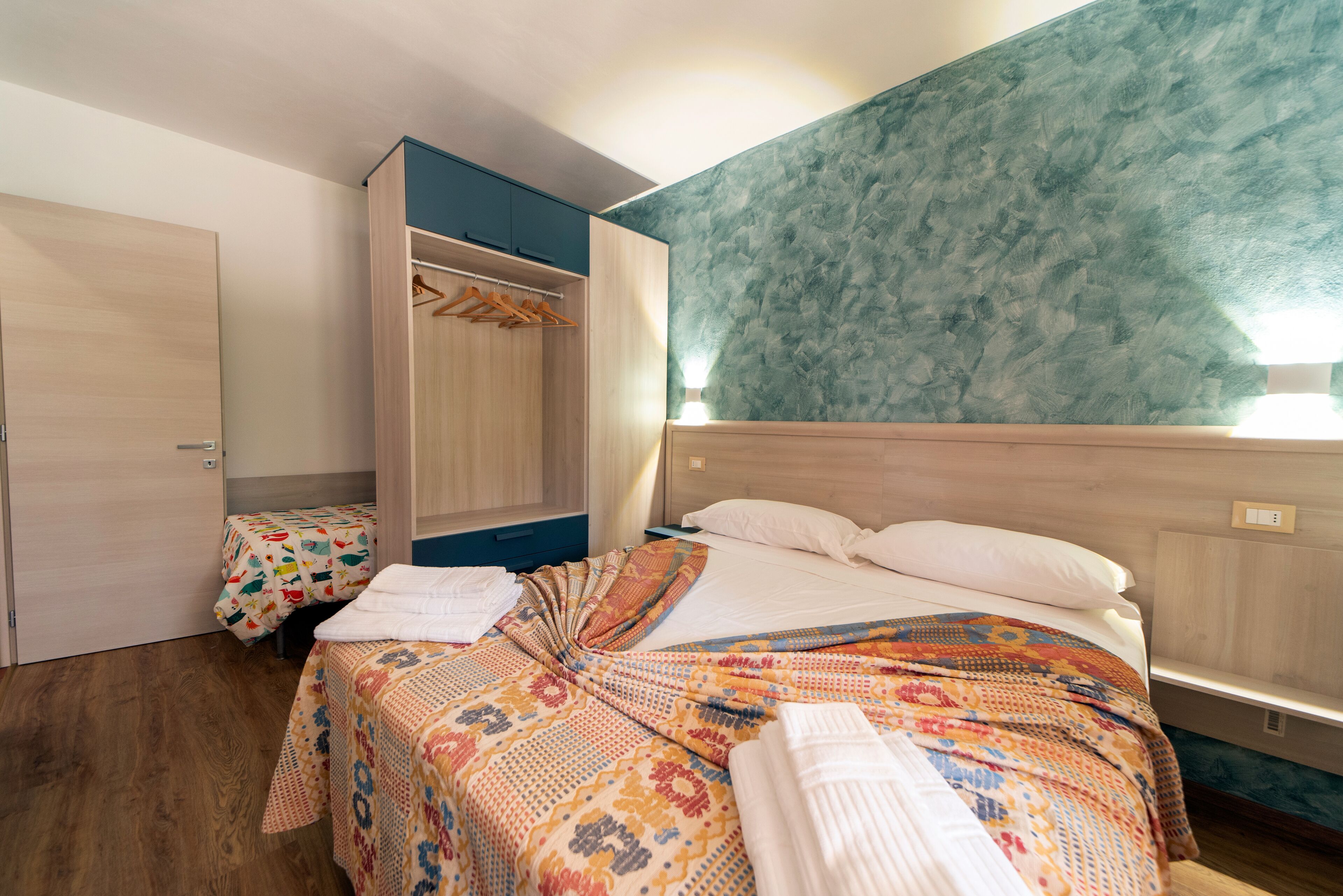 A bedroom with a bed, a wardrobe, and a mirror.