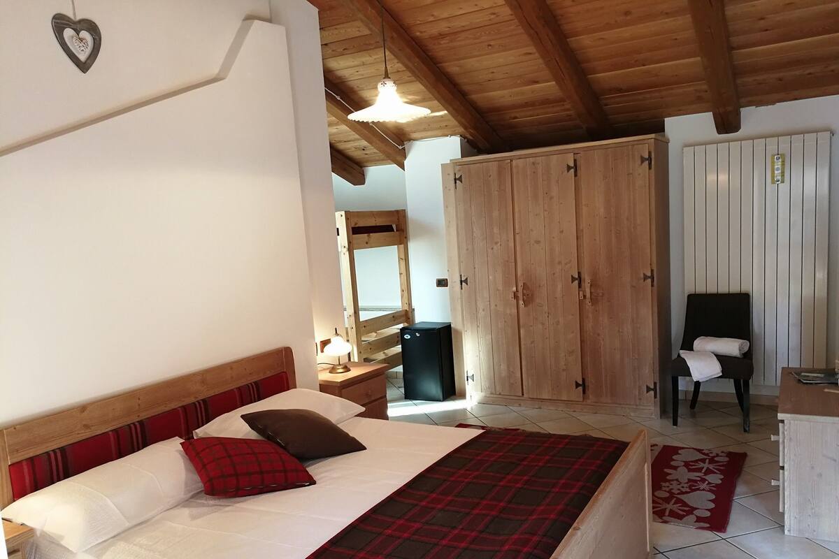 Un dormitorio con una cama, un armario de madera, una silla y un escritorio.