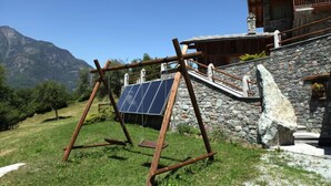 Una estructura de madera rústica con un panel solar, con montañas al fondo.
