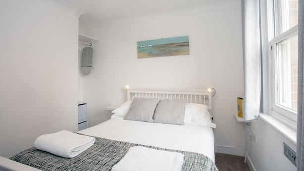 Una camera da letto ordinata con un letto, un quadro e una finestra con tende.