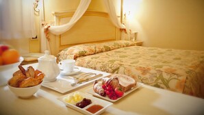 A breakfast setup with croissants, strawberries, and jam on a tray, a pitcher, and a cup on a table in a room with a bed and floral bedding. - Ca' Matilde (Quattro Castella)
