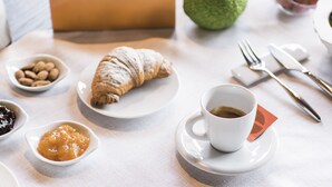 A breakfast setting with croissants, coffee, and small bowls of jam and nuts on a table. - Ca' Matilde (Quattro Castella)