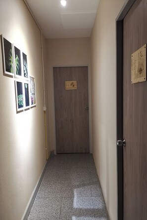 A hallway with a door, a wall-mounted plaque, and framed artwork. - Foresttel.bkk (Bangkok)