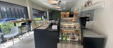 A modern cafe interior with a counter, seating area, and a display case with beverages.