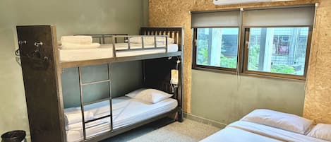 A bunk bed room with a window, a wall-mounted air conditioner, and a pair of slippers on the floor.