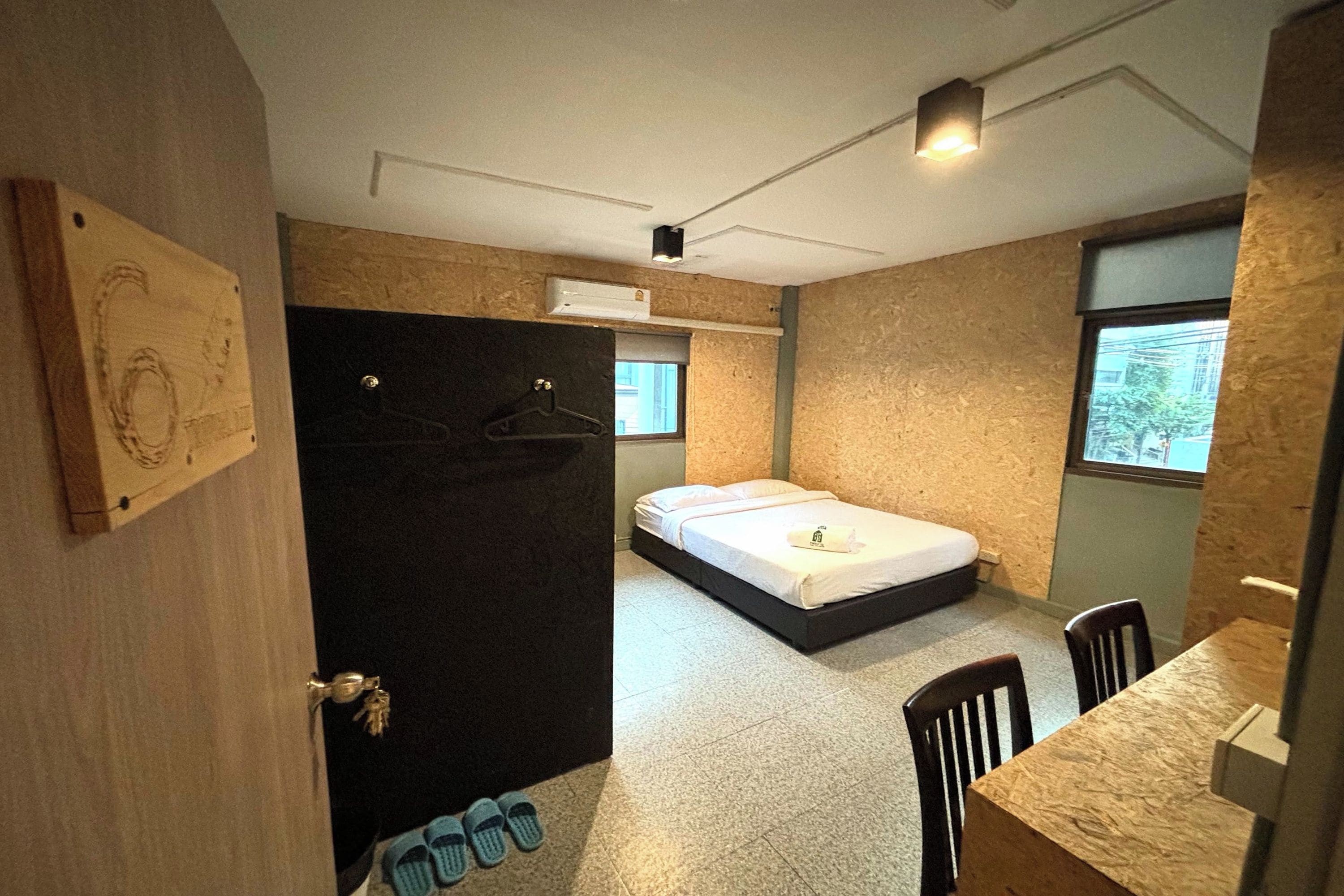A compact bedroom with a bed, a small table, and a chair.