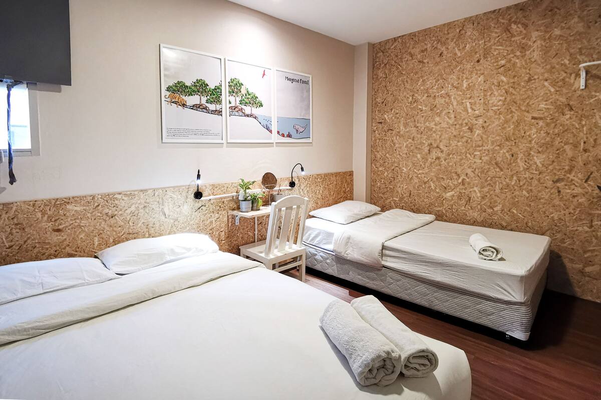Ein Hotelzimmer mit zwei Betten, einem kleinen Tisch mit Spiegel und einem Kunstwerk an der Wand.