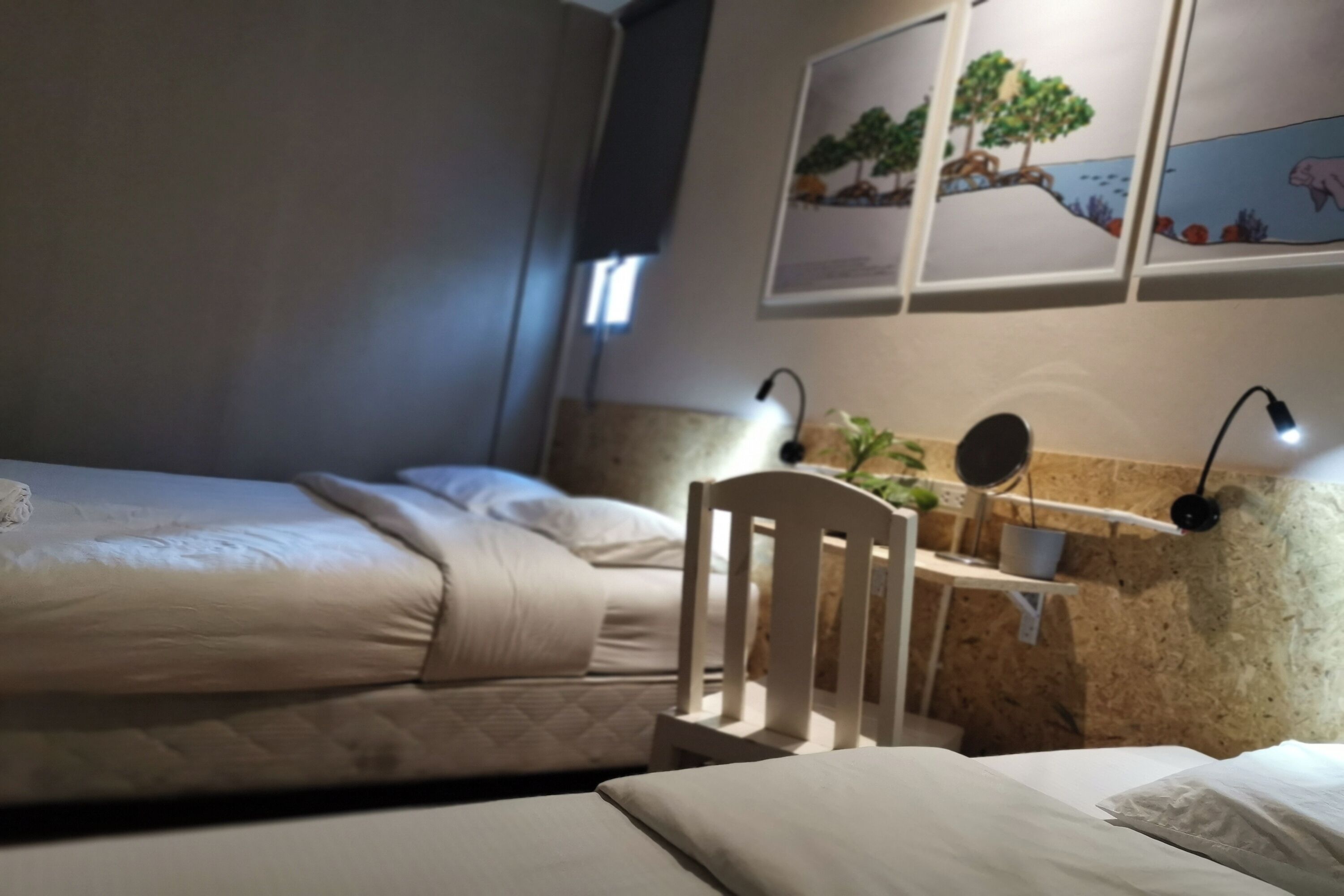 Ein Schlafzimmer mit zwei Betten, einem Schreibtisch mit Stuhl und Wandleuchten.