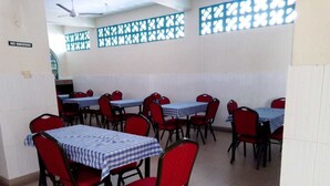 A dining area with tables and chairs, a 'NO SMOKING' sign, and decorative window screens. - Metric Annex Hotel (Mombasa)