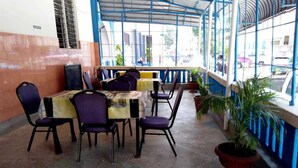 An outdoor cafe with tables and chairs, a potted plant, and a view of the street. - Metric Annex Hotel (Mombasa)