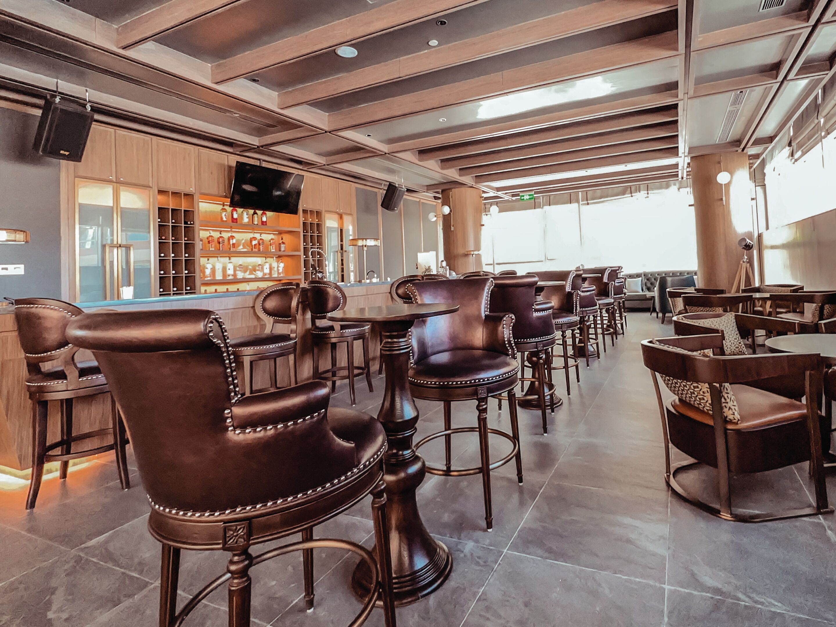A modern bar area with leather barstools and a wine display.